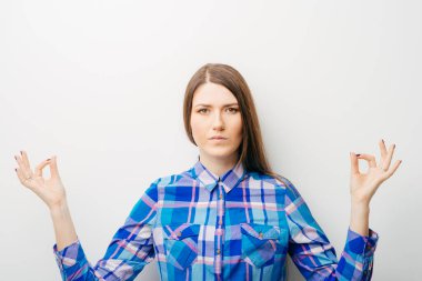 Beyaz bir arka planda genç bir kız meditasyon yapıyor.