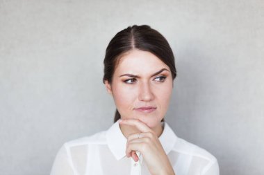 Oldukça çılgın genç bir kadının yakın plan portresi, parmakları dudaklarda, ciddi ve üzücü bir şey hayal ediyor. İnsan yüz ifadeleri, duygular, duygular, işaretler, semboller
