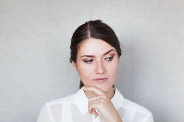 Oldukça çılgın genç bir kadının yakın plan portresi, parmakları dudaklarda, ciddi ve üzücü bir şey hayal ediyor. İnsan yüz ifadeleri, duygular, duygular, işaretler, semboller