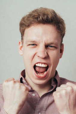 Adam yumruklarını sıkar ve bağırır.