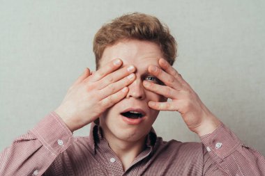 Adam parmaklarının arasından dikizliyor.