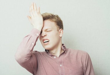 Üzgün adam, alnını eliyle tutuyor.