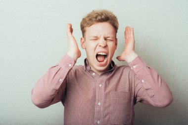 Öfkeli genç adamlar ellerini tutup çığlık atıyorlar.