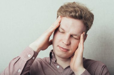 Baş ağrısı çeken genç bir adam.