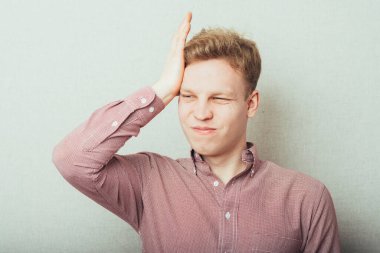 Elleri başının üstünde üzgün genç bir adam.