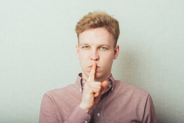 Adam işaret parmağını dudaklarına koyuyor, sessiz olduğunu gösteriyor.