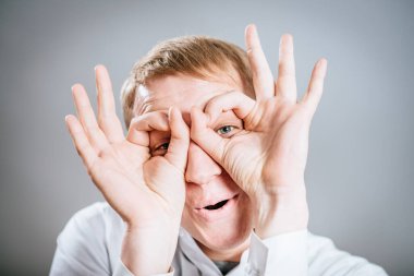 Gri arka planda duran genç ve komik bir adamın portresi..