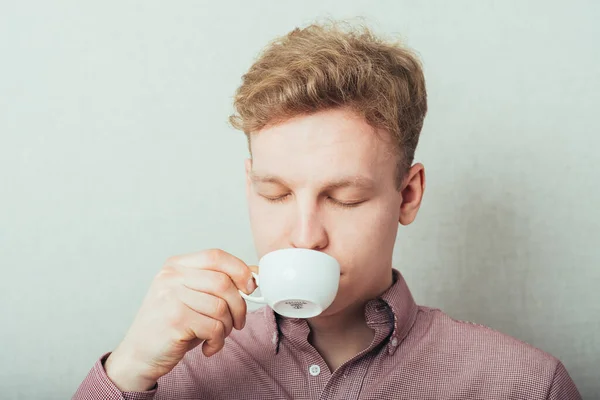 man drinks coffee from a small white cup of coffee