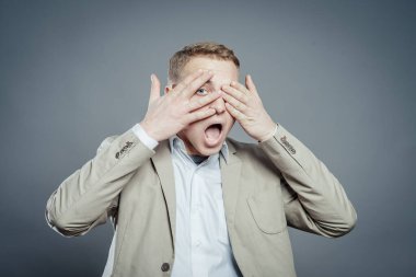 İfadeler. Takım elbiseli yakışıklı genç adam korkuyu hissetti ağzı açık ve elleri kapalı gözleri.