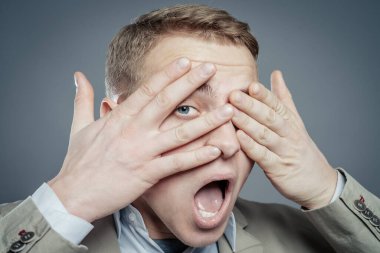 İfadeler. Takım elbiseli yakışıklı genç adam korkuyu hissetti ağzı açık ve elleri kapalı gözleri.