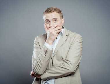 İş adamı elleri ile ağzını kapatır, korku, kükremek istemez, güler.