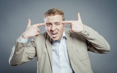 Parmağıyla şakağına dokunan öfkeli bir adamın yakın plan portresi. Delirdin mi sen??