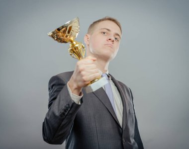 Altın bir kupanın portresi. Kazanan iş adamı gururla kupayı gösteriyor. Kazanma ve başarı kavramı