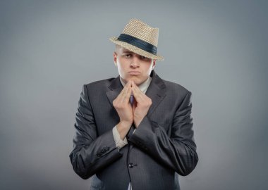 Yakın plan, şapkalı çaresiz genç adam sıkıca sarılmış elleri gösteriyor, lütfen izole edilmiş gri duvar arkaplanının üstüne. İnsan duyguları yüz ifadeleri duygular, işaretler vücut dili.