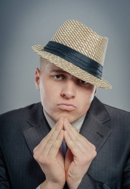 Yakın plan, şapkalı çaresiz genç adam sıkıca sarılmış elleri gösteriyor, lütfen izole edilmiş gri duvar arkaplanının üstüne. İnsan duyguları yüz ifadeleri duygular, işaretler vücut dili.