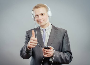 Modern iş adamının kulaklıklarla müzik dinleyip dans ettiği bir stüdyo fotoğrafı.