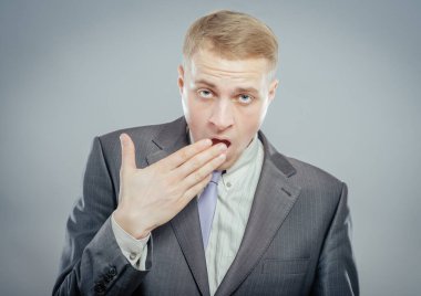 Gri arka planda esneyen iş adamı