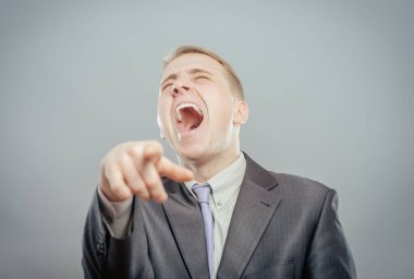 Takım elbiseli adam gülüyor ve parmağıyla işaret ediyor.