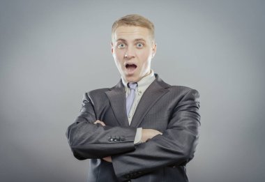 Genç ve yakışıklı bir adam gri arka planda mahsur kalmış.