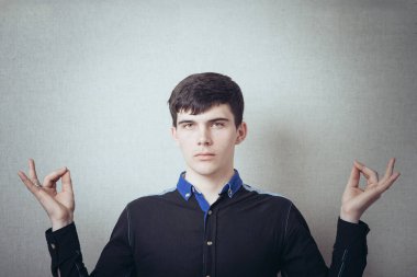 Adam meditasyon yapıyor. Hı hı. Rahatlama. Jest yap. Gri bir arkaplanda.