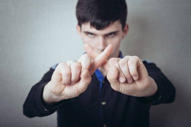 Genç adam durduğunu göstermek için parmaklarını çapraz yaptı.