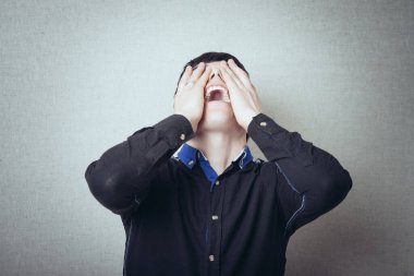 Gri arka planda ağlayan bir adam var.