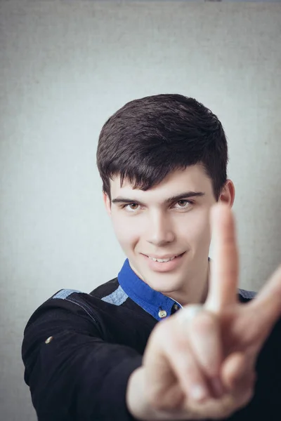 Young Man Makes Gesture Victory Gray Background — Stock Photo, Image