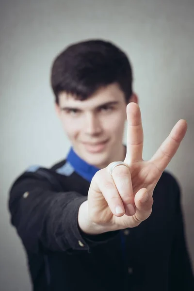 Young Man Makes Gesture Victory Gray Background — Stock Photo, Image