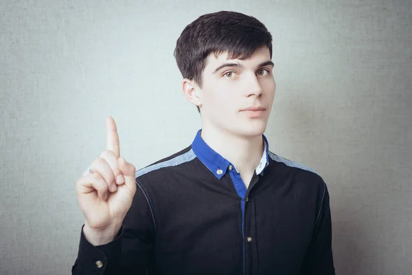 Junger Mann Mit Erhobenem Zeigefinger Auf Grauem Hintergrund — Stockfoto
