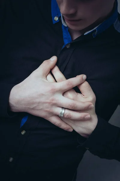 Man hands on his chest, a sore heart. Gesture heart aches attack. On a gray background