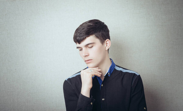 Handsome young man pensive and looking at side isolated on a gray background