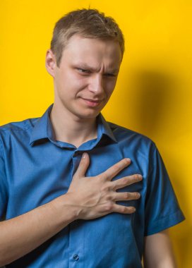 Sarı arka planda kalp ağrısı çeken genç bir adam.