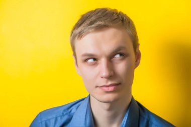 Sarı arka planda mavi gömlekli genç adam, düşünceli, sanatsal, planlı bir şey. Taklit. Jest yap. fotoğraf çekimi