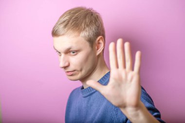 Dur durağı gösteren genç adam. Jest yap. Mor bir arka planda.