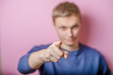 Genç adam parmağıyla birini işaret ediyor.