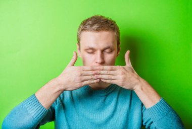 Genç adam elleriyle ağzını kapatıyor.