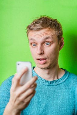 Kafası karışmış genç bir adam cep telefonuna bakıyor.