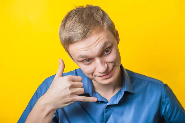 Jongeman Een Blauw Shirt Een Gele Achtergrond Lachende Shows Bellen — Stockfoto