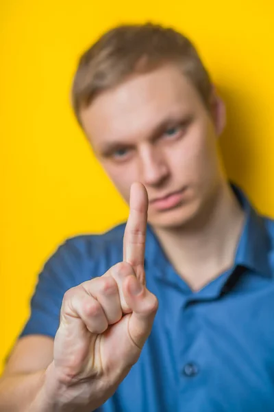 Sarı Arka Planda Mavi Gömlekli Genç Bir Adam Işaret Parmağınızı — Stok fotoğraf
