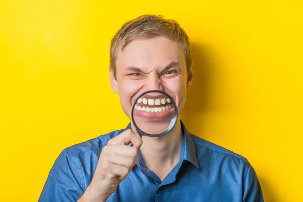 Ung Man Närbild Blå Skjorta Gul Bakgrund Håller Ett Förstoringsglas — Stockfoto