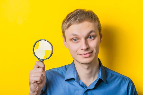 Ung Man Närbild Blå Skjorta Gul Bakgrund Med Ett Förstoringsglas — Stockfoto