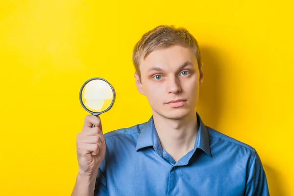 Ung Man Närbild Blå Skjorta Gul Bakgrund Med Ett Förstoringsglas — Stockfoto