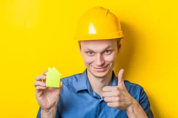 Joven Con Casco Sosteniendo Una Casa Papel Sobre Fondo Amarillo — Foto de Stock