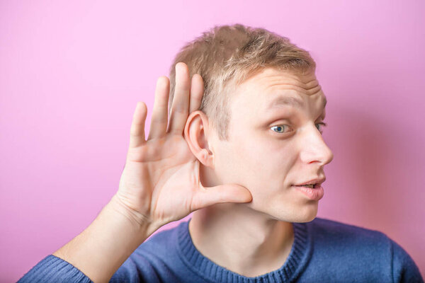A young man trying to hearing the sound around him - What did you say?