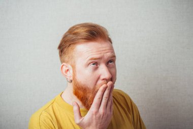 Sakallı adam elleriyle ağzını kapatarak esniyor.