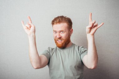 Çekici genç kızıl sakallı adam Rock 'n Roll' un el hareketlerini gösteriyor. 