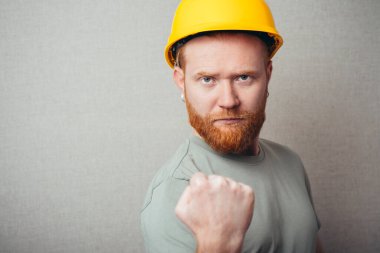 İnşaat işçisi genç hippi, sakallı, yumruğunu sıkmış bir adam.