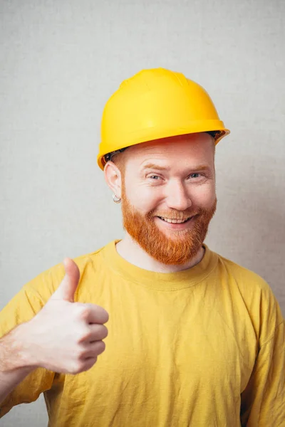 Gray Background Man Beard Yellow Shirt Yellow Construction Helmet Showing — Stock Photo, Image