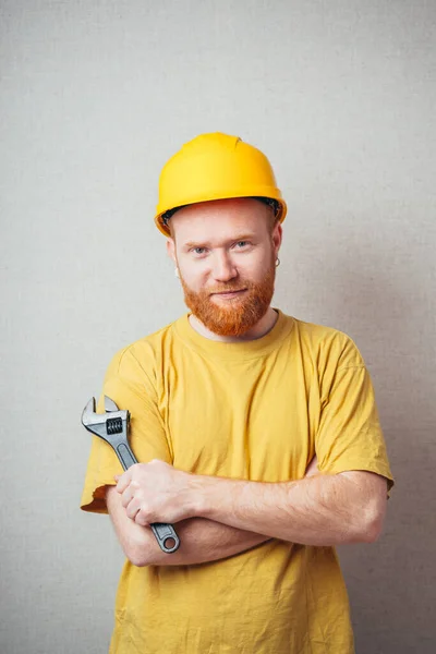 Šedém Pozadí Muž Vousy Žluté Košili Žluté Stavební Přilbě Drží — Stock fotografie