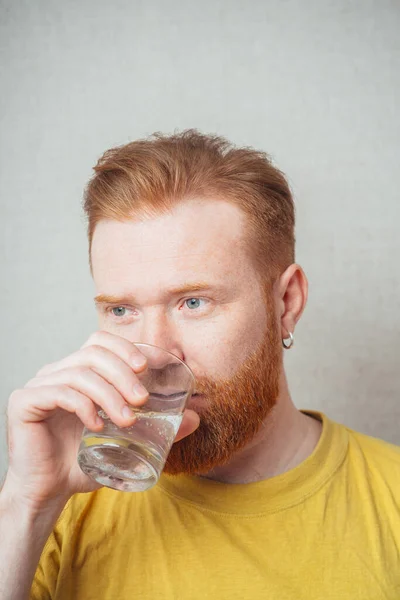 Uno Sfondo Grigio Uomo Con Barba Una Shirt Gialla Beve — Foto Stock